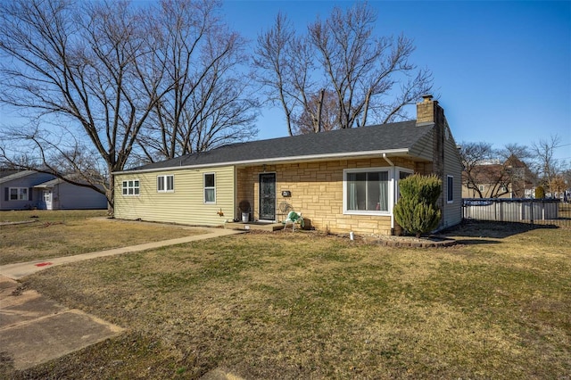 view of front of house with a chimney, a shingled roof, a front yard, fence, and stone siding