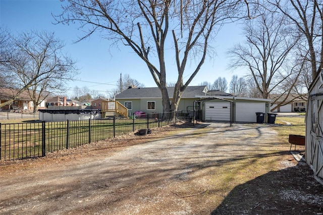 view of front of property featuring driveway, a garage, a residential view, fence, and an outdoor structure