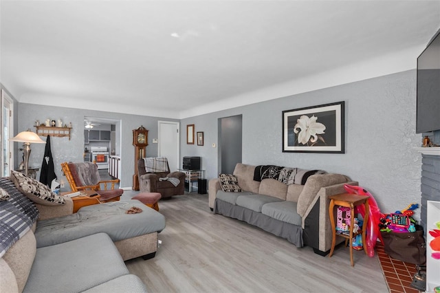 living area featuring ceiling fan, a fireplace, and wood finished floors