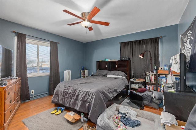 bedroom with a baseboard radiator, wood finished floors, and a ceiling fan