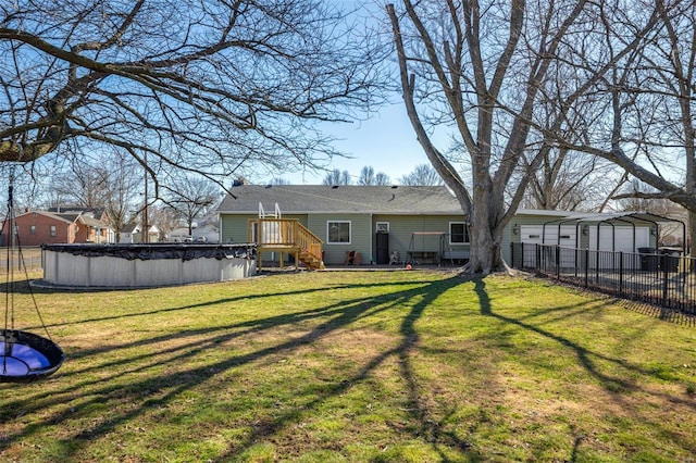 rear view of property with a covered pool, fence, a wooden deck, and a yard