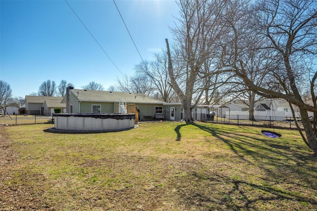 rear view of house with a fenced in pool, a lawn, and fence