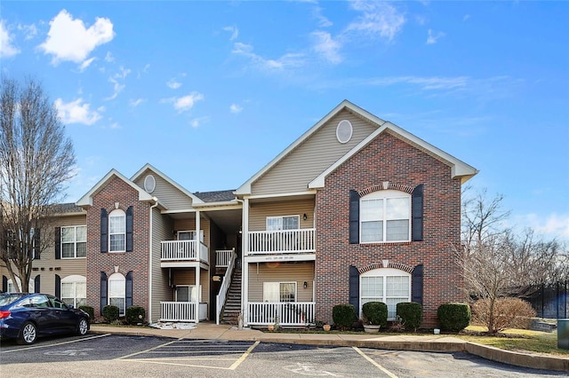 view of property with stairway and uncovered parking