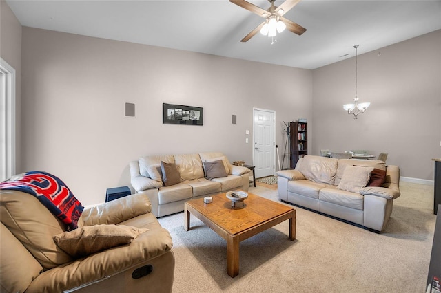 carpeted living room with ceiling fan with notable chandelier and baseboards