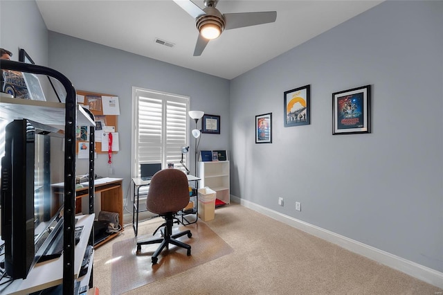 home office with visible vents, baseboards, light colored carpet, and a ceiling fan