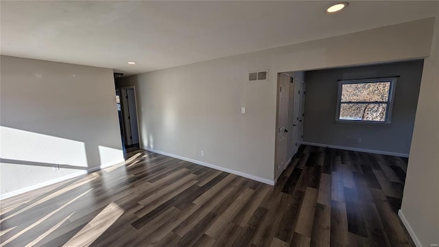 spare room featuring baseboards, visible vents, dark wood-style flooring, and recessed lighting