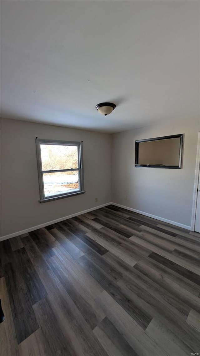 unfurnished room featuring dark wood-style floors and baseboards