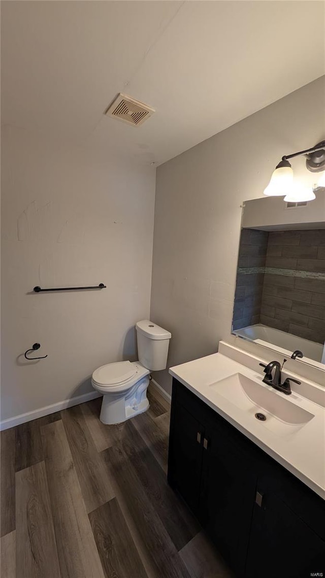 full bath with toilet, wood finished floors, vanity, visible vents, and baseboards