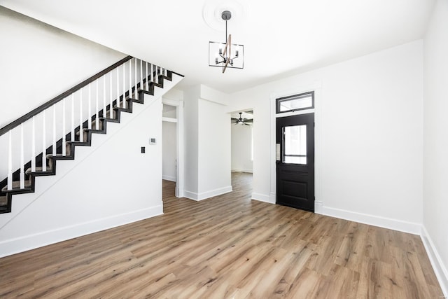 foyer featuring stairs, an inviting chandelier, wood finished floors, and baseboards