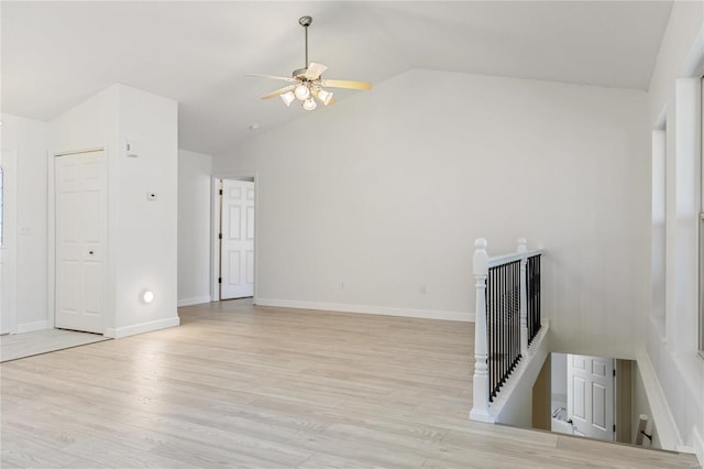 unfurnished living room featuring light wood-type flooring, ceiling fan, baseboards, and vaulted ceiling