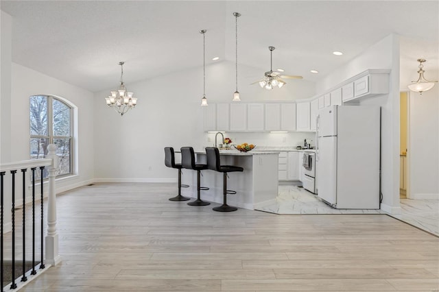 kitchen with white appliances, white cabinets, light countertops, light wood-style floors, and a kitchen bar