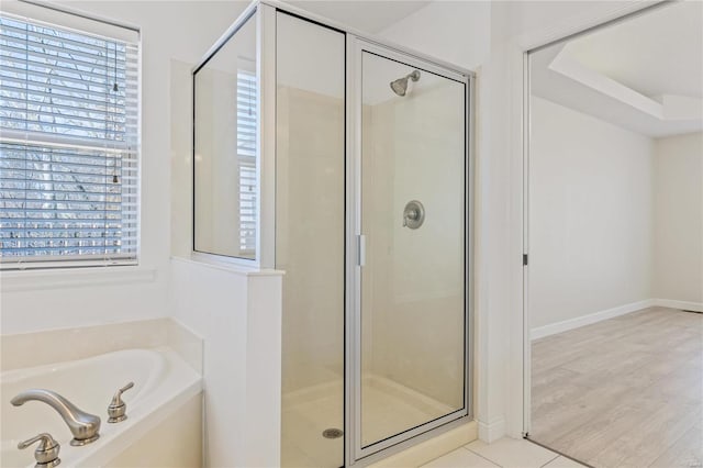 full bath with wood finished floors, plenty of natural light, a shower stall, and a bath