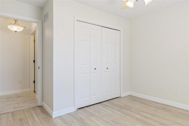 unfurnished bedroom with a closet, baseboards, visible vents, and light wood finished floors