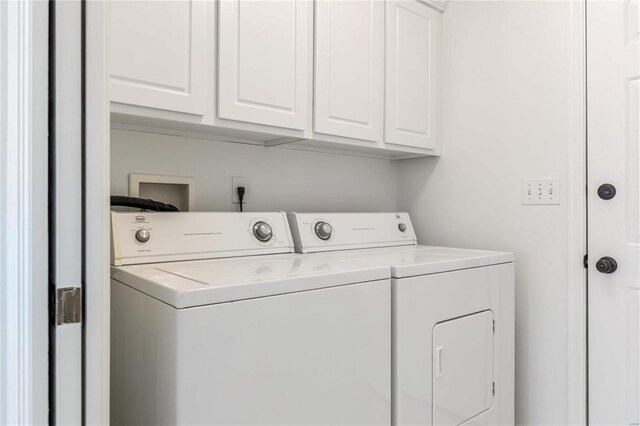 clothes washing area featuring cabinet space and washer and clothes dryer