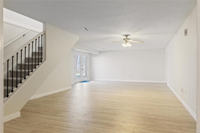 unfurnished living room with visible vents, ceiling fan, light wood-style flooring, and stairs