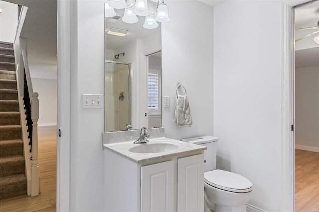 bathroom with toilet, an enclosed shower, wood finished floors, and vanity