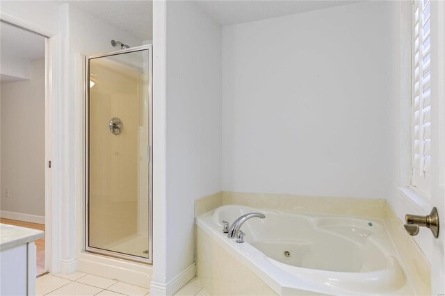 bathroom featuring baseboards, tile patterned floors, a garden tub, vanity, and a shower stall