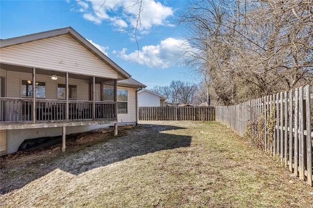 view of yard with ceiling fan, a fenced backyard, and a sunroom