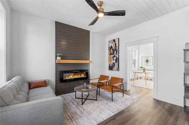 living room featuring a large fireplace, wood finished floors, wood ceiling, a ceiling fan, and baseboards