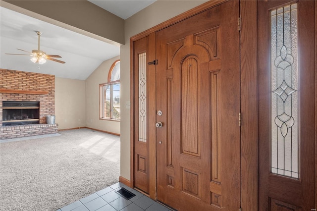 carpeted entryway with baseboards, visible vents, ceiling fan, vaulted ceiling, and a brick fireplace