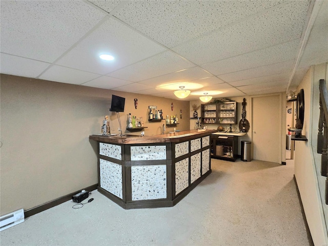 bar featuring a baseboard radiator, baseboards, a paneled ceiling, and a bar