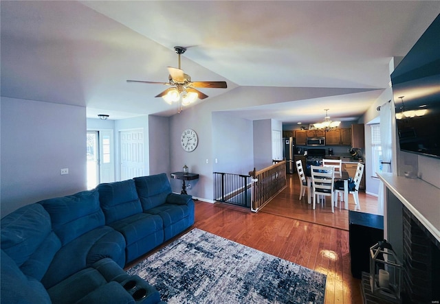 living room with ceiling fan with notable chandelier, baseboards, lofted ceiling, and wood finished floors