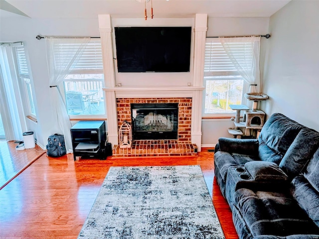 living area with a brick fireplace, wood finished floors, and baseboards