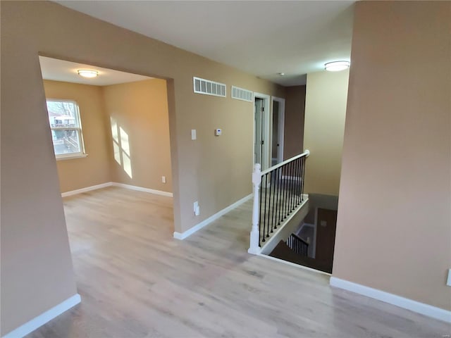 unfurnished room with wood finished floors, visible vents, and baseboards