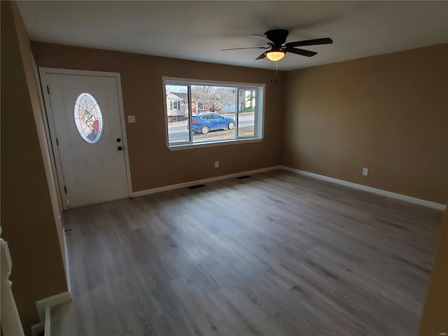 foyer featuring a ceiling fan, visible vents, baseboards, and wood finished floors