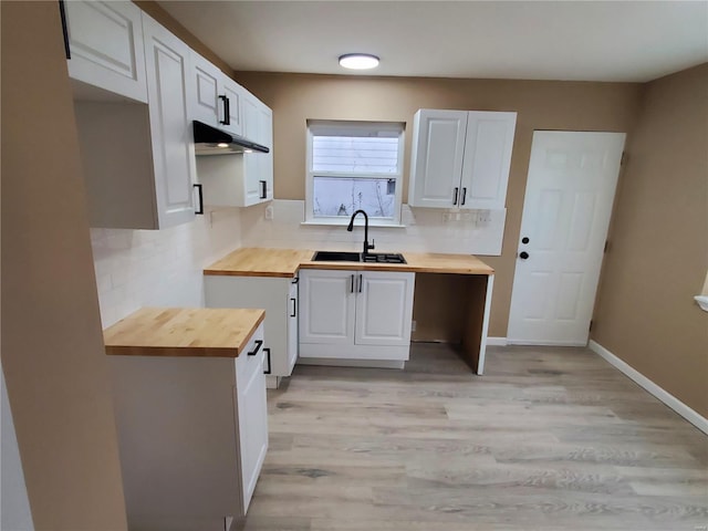 kitchen featuring white cabinetry, decorative backsplash, wooden counters, and a sink