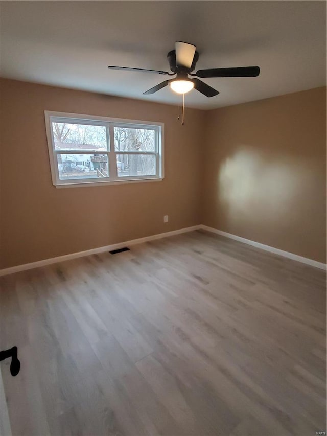 empty room with visible vents, baseboards, ceiling fan, and wood finished floors