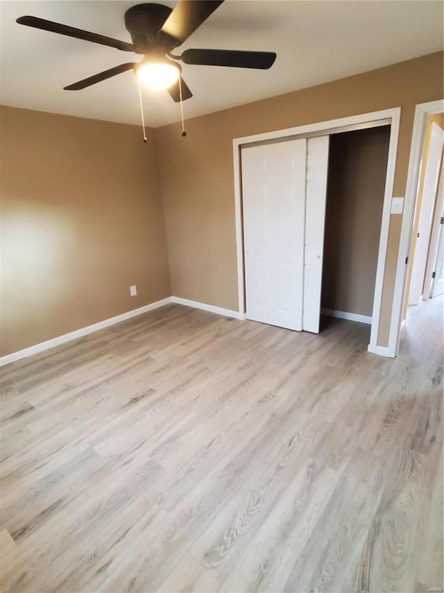 unfurnished bedroom featuring a closet, wood finished floors, a ceiling fan, and baseboards