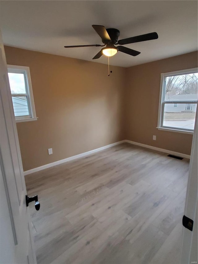 empty room with a healthy amount of sunlight, visible vents, baseboards, and light wood finished floors