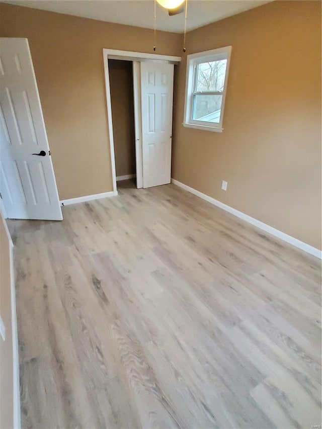 unfurnished bedroom featuring light wood finished floors, a closet, and baseboards