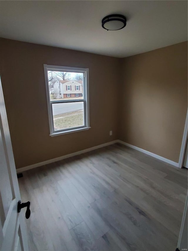 unfurnished room with baseboards and wood finished floors