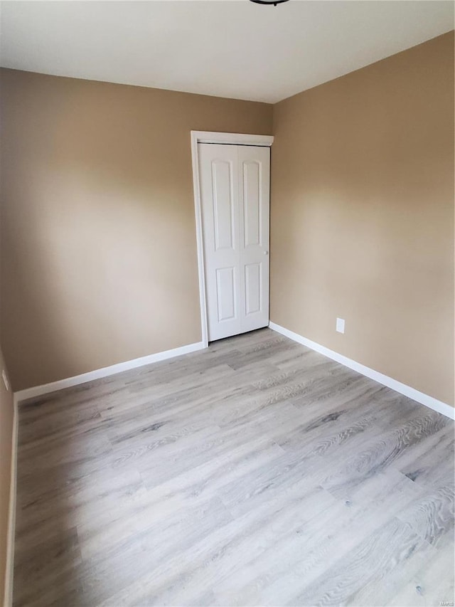 unfurnished bedroom with light wood-style floors, baseboards, and a closet