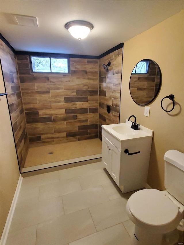 full bathroom featuring a tile shower, vanity, and toilet