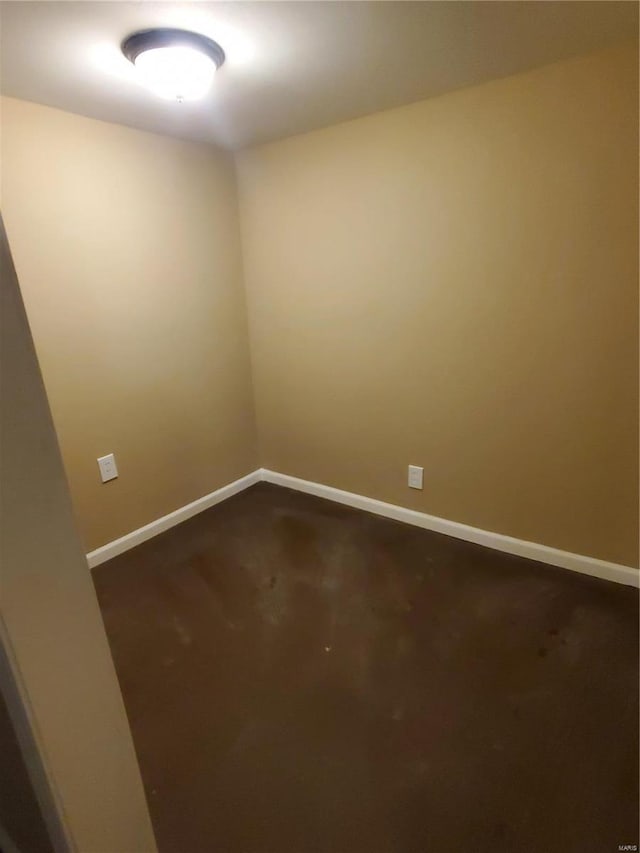 empty room featuring dark carpet and baseboards