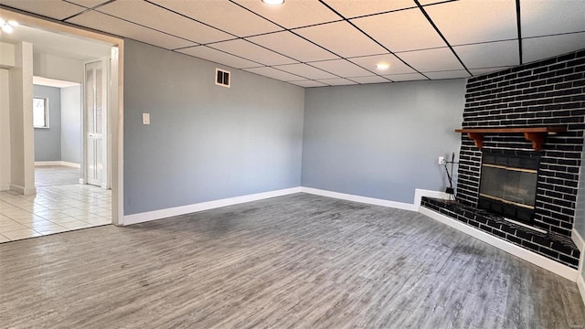 unfurnished living room with wood finished floors, a fireplace, visible vents, and baseboards