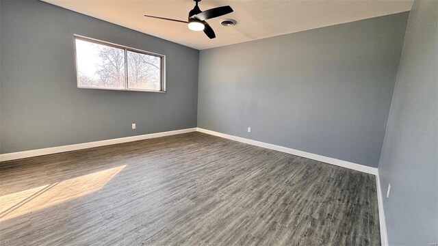 unfurnished room with visible vents, baseboards, dark wood-type flooring, and a ceiling fan