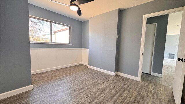 unfurnished room featuring a ceiling fan, wood finished floors, visible vents, and baseboards