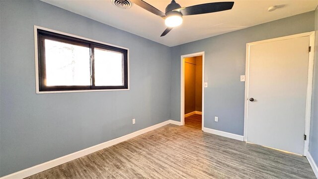 unfurnished bedroom featuring visible vents, baseboards, wood finished floors, and a ceiling fan