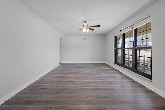 unfurnished room with a ceiling fan, wood finished floors, visible vents, and baseboards