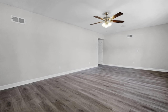 empty room featuring dark wood-style floors, baseboards, visible vents, and a ceiling fan