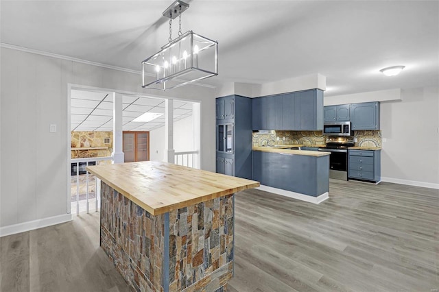 kitchen with decorative backsplash, appliances with stainless steel finishes, blue cabinets, a peninsula, and wooden counters