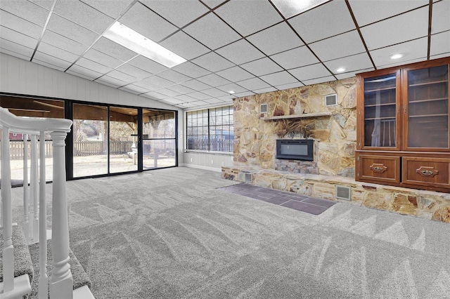 unfurnished living room featuring lofted ceiling, carpet floors, a stone fireplace, and visible vents