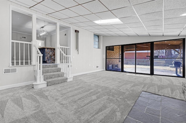 unfurnished living room featuring a paneled ceiling, visible vents, stairway, carpet flooring, and baseboards