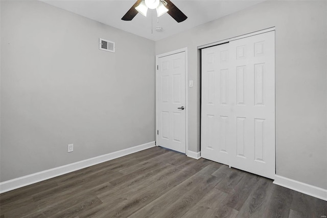 unfurnished bedroom featuring dark wood-style floors, baseboards, visible vents, and a closet