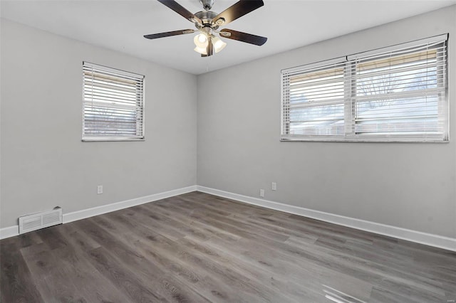 unfurnished room featuring baseboards, visible vents, and wood finished floors