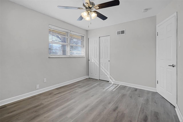 unfurnished bedroom featuring visible vents, a closet, baseboards, and wood finished floors